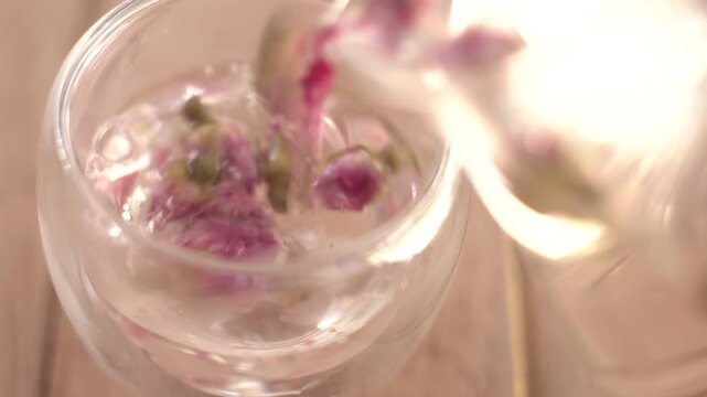 Close-up of hot organic rose tea being poured from a teapot into a clear glass cup, healthy herbal beverage for relaxation and wellness, rich in antioxidants and vitamins for healthy skin.