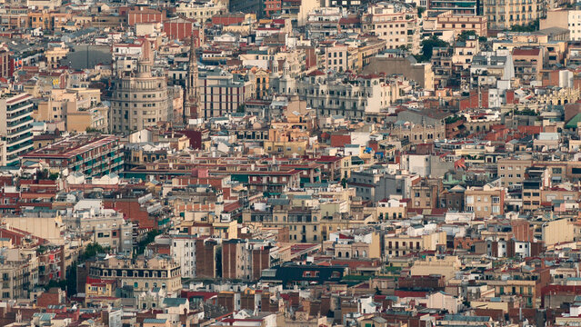 Super-telephoto elevated view of Barcelona's dense urban landscape, showing the traditional rooftops, balconies, and historical architecture of the Eixample and Gracia districts, captured from Tibidab