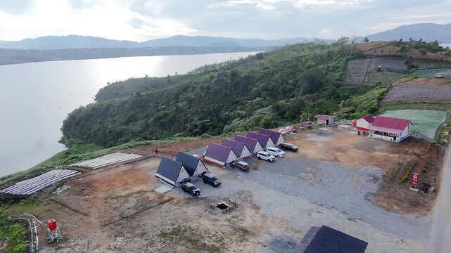 Aerial view of Danau Diatas lake with lakeside cabins in Alahan Panjang, West Sumatra, Indonesia. High angle drone shot of beautiful highland lake landscape and eco-resort.
