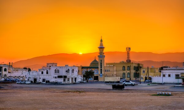 Golden sunset glow illuminates Aisha Makha Mosque and traditional Omani architecture in the coastal city of Sur in Oman