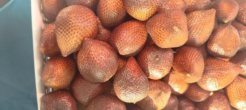 A close-up view of a pile of ripe salak fruit, also known as snake fruit, showcasing their unique scaly skin