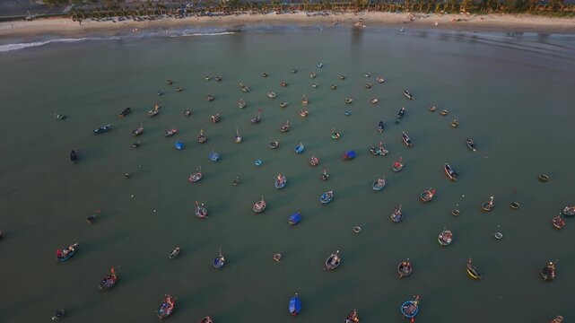 Vietnam, Da Nang Low Altitude Aerial Of Da Nang Nearshore Coracles Scattered Along Beachfront, Asian Fishers In Round Boats And Visible Coastal Buildings Framing Shallow Water Scene