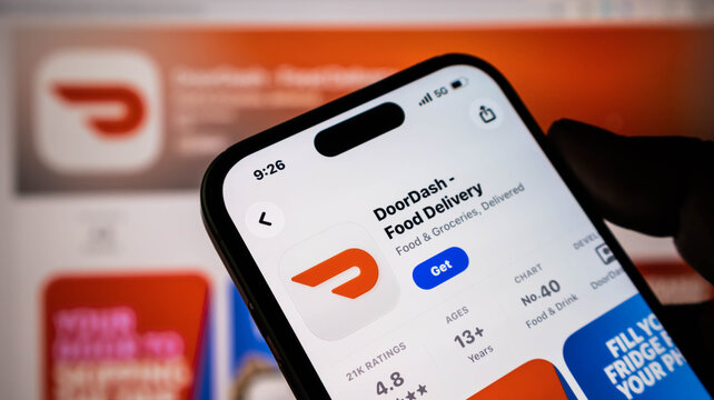 Closeup of a smartphone screen displaying the doordash food delivery app in the apple app store, showing ratings, age requirements, and ranking