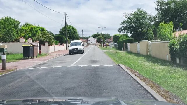 Blue SUV and White Van Driving on Suburban French Road
