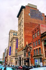Obraz premium A view of historic architecture along Calvert Street in downtown Baltimore, Maryland, United States. The scene features a mix of brick and stone commercial buildings on an overcast day