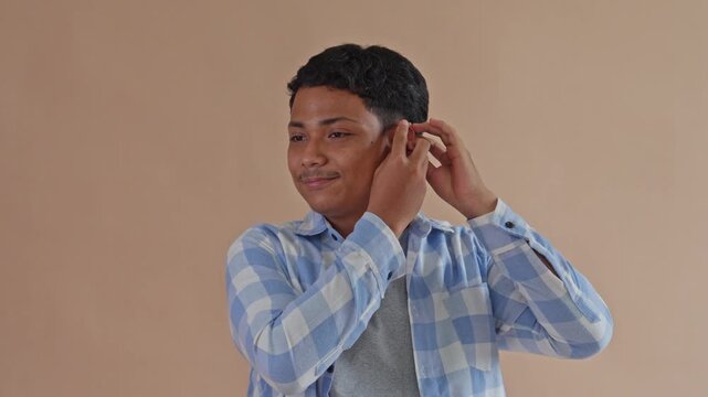 Young Man Successfully Fitting Behind-The-Ear Hearing Aid And Giving Thumbs-Up