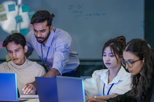 A senior software architect reviewing database schemas and machine learning code variables on a laptop display with a junior programmer.