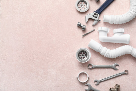 Set of plumber's items on pink grunge background