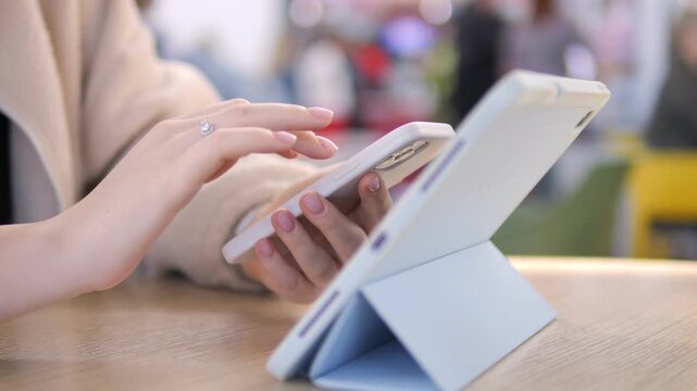 Person holds tablet with stylus. Hand interacts with screen. Light blue case supports device. Blurred background shows indoor setting