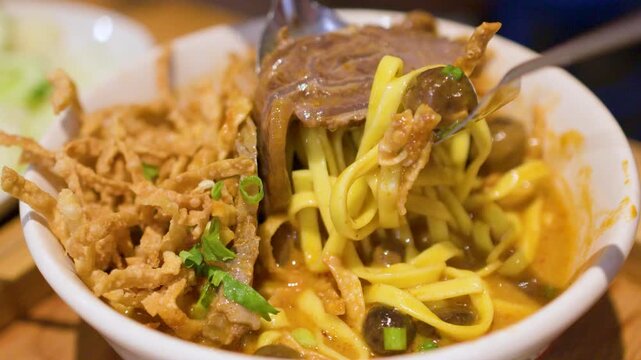 Close Up of Person Eating Northern Thai Khao Soi Curry Noodles