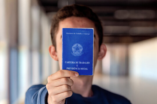  Young Man Holding Brazilian CTPS Work Card Indoors, Employment and Labor Rights Concept