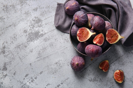 Bowl with fresh ripe figs on grey background