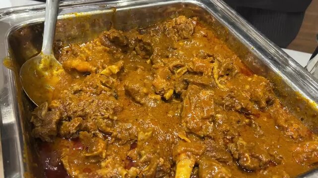 A premium buffet presentation of traditional, slow-cooked mutton curry featuring tender meat in a rich, aromatic gravy, served as a luxury centrepiece at an upscale Indian marriage reception.