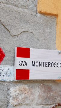 Vertical panning shot of hiking sign pointing to Monterosso on wall in Vernazza Cinque Terre