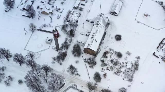 Winter settlement with snow covering houses and bare trees, cold season environment, aerial top down view