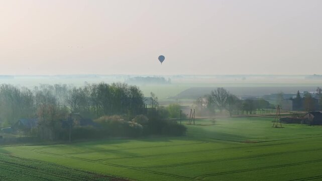 Misty spring Latvia layered fields soft haze rising sun tones balloon floating