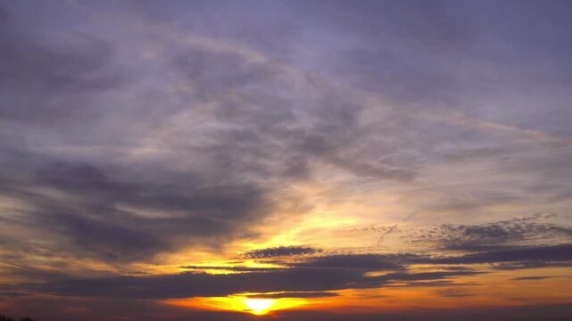 The sun appeared to set behind the western horizon, emitting a bright golden and orange glow through the clouds.