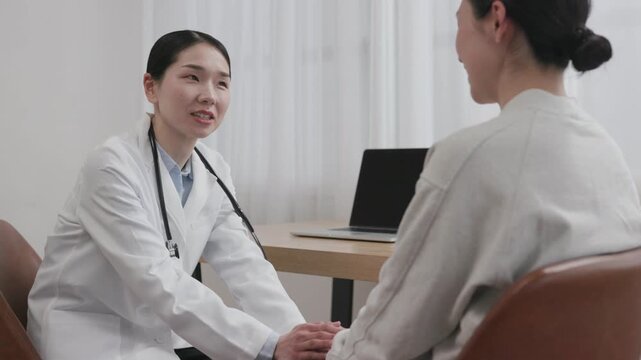 Asian Female Doctor Holding Patient Hand with Warm Smile to Encourage