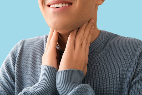 Young man with thyroid gland problem on blue background, closeup