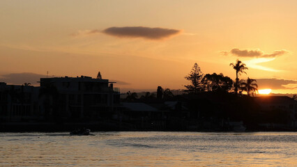 Naklejka premium Sunset Over Silhouetted Waterfront Homes and Palm Trees by the Water