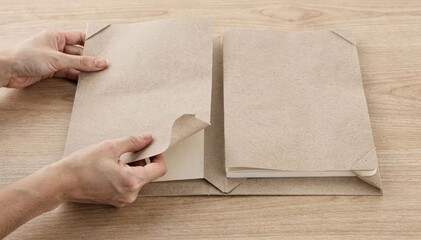 Obraz premium Medium shot focusing on assembling a card wrap cover for a layflat notebook highlighting folding techniques and protective corner shaping on a wooden table.