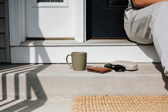Morning coffee mug wallet and sunglasses on front porch step