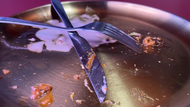 Dirty plate with knife and fork. Photo can be used for the concept of how to clean the plate after food. Extreme Close up view. Detail. Texture, textured. Eating. stainless steel. grey, gray. yellow, 