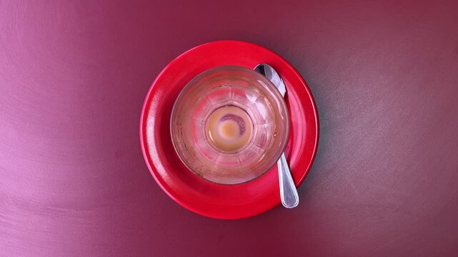 Photo of empty coffee cup after drinking. glass with stainless steel spoon. red table. Cafe, coffe shop, restaurant. Close up view. high angle, above, flat lay. little, tea. isolated. purple, voilet, 