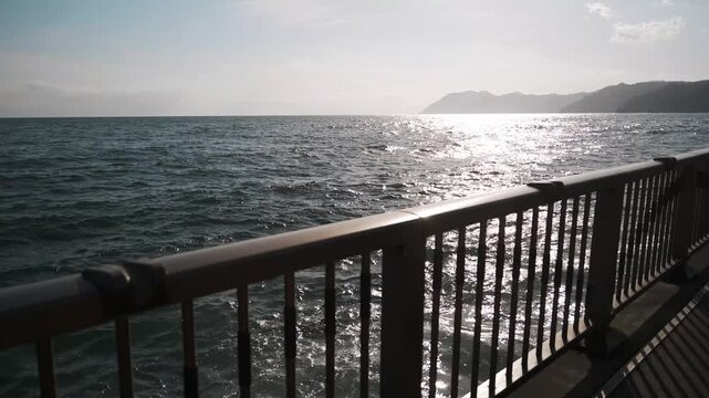 A coastal deck fence with a reflective ocean surface in the background