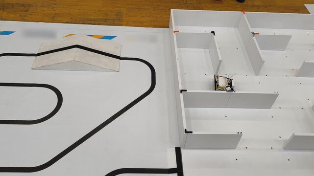 Top view - a robot moves through a maze on a competitive field for robotics, STEM, programming, engineering training.
