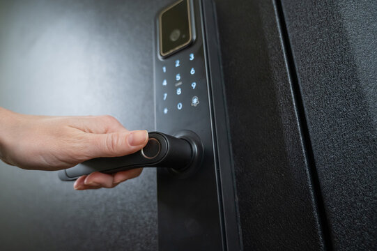 A woman opens a modern smart door lock with a digital keypad and biometric fingerprint access.