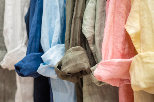 Various range of linen colorful shirts hanging on display at fashionable clothing store, collection of new trendy summer shirts on hangers showcased at fashionable showroom, apparel retail industry.