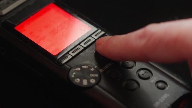 Macro close-up of a finger activating record as a red indicator glows, suggesting surveillance, evidence capture, or the beginning of a controlled recording session.