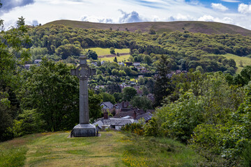 Celtic cross war memorial stands on elevated ground above Church Stretton with the town and wooded hillside beyond © Philip