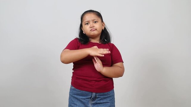 Asian little girl standing, looking at camera and showing timeout gesture sign.