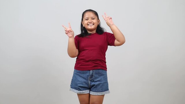 Asian little girl joyful and carefree showing a peace symbol with fingers
