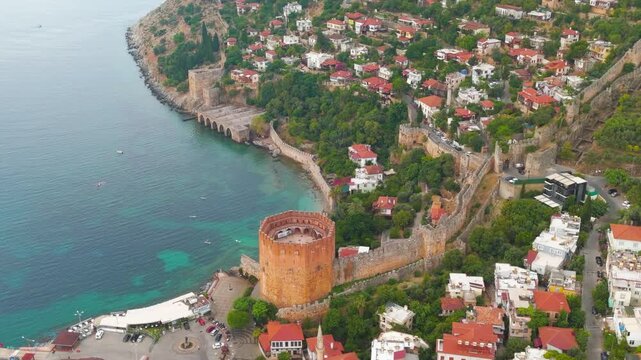 Alanya, Turkey. Kizilkule Red Tower, octagonal Seljuk brick fortress rising above the Mediterranean coastline, dynamic aerial orbit revealing harbor and ancient walls. Aerial View, MasterShots, Spira