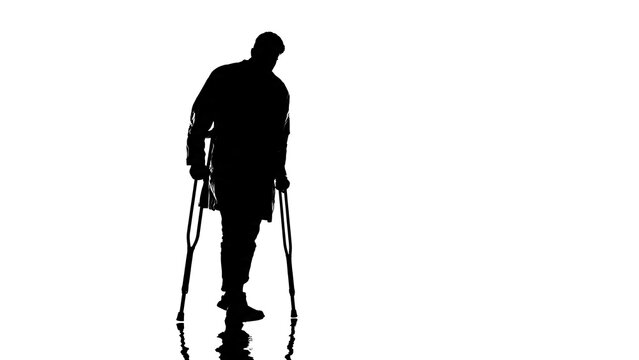Man walking with crutches silhouette.