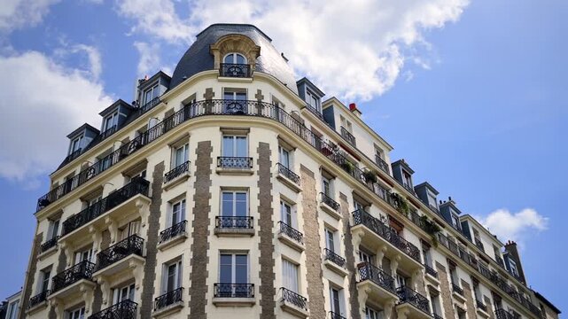 Classic parisian architecture building exterior with blue sky and white clouds low angle cinematic shot.
