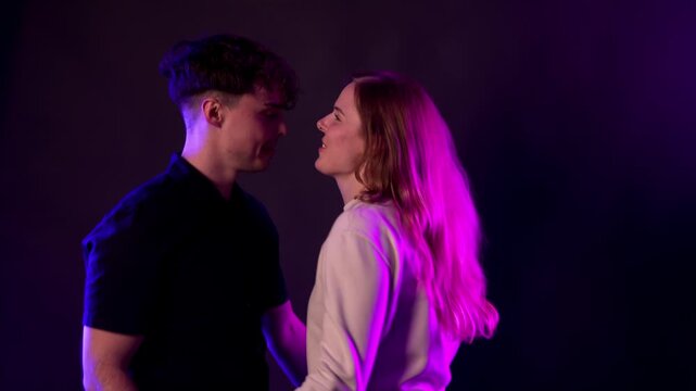 A young couple shares a moment of love and fun, laughing and flirting under vibrant neon lighting. This scene captures their romantic connection and happiness, making it projects related to relationsh