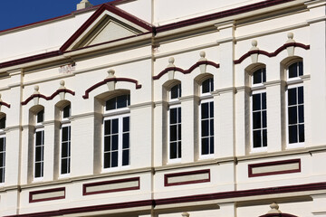 Architectural close-up of a historic building facade featuring elegant classical windows, ornate decorative trim, and traditional white plaster walls © Tammy Walker