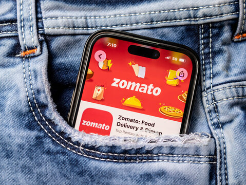 Smartphone displaying zomato app screen in a jeans pocket for food delivery