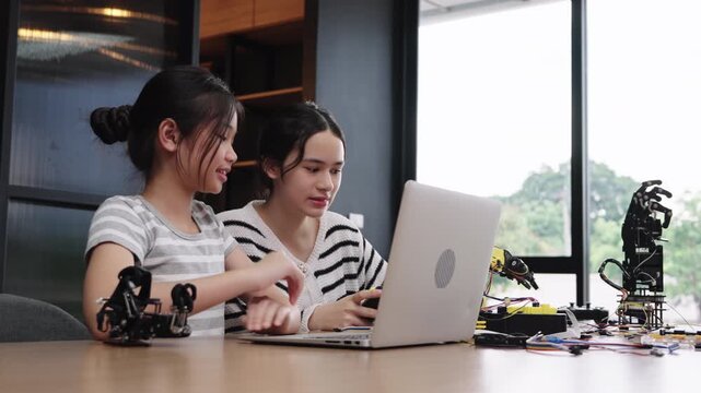 Asian students learning robotics and STEM technology with laptop together.