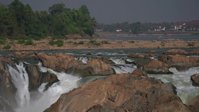 Camera looking upstream along the Mekong river then tilting down to reveal the Khone Phapheng falls. Shot with a long focal length and in slow motion.