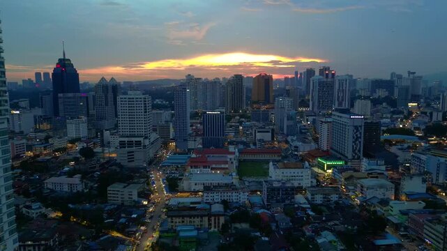 Evening cityscape showing residential and commercial buildings during sunset. Smooth aerial view fly reverse panorama drone