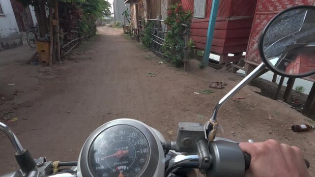 Point of view shot riding along the west coast road of Don Det past small houses build along the Mekong river.