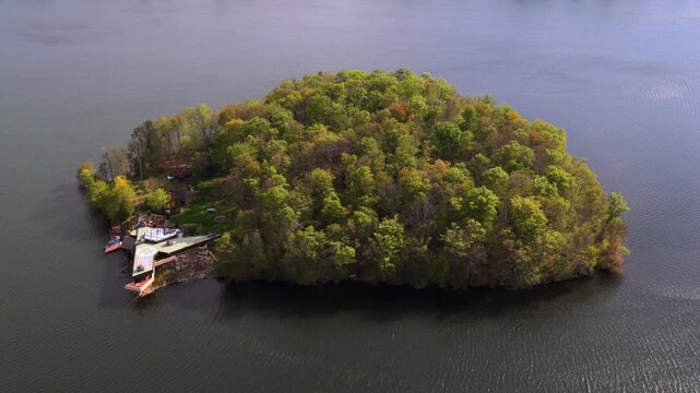 Aerial view of the Massaro House on Petre Island upstate. A unique triangular house on the shoreline, with a helipad, skylight panels and trees. The camera tilted down, slowly truck right and pan left