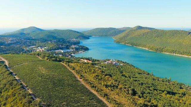 Abrau-Diurso, Krasnodar Krai, Russia. Lake Abrau, the largest freshwater lake in the region, nestled in a deep mountain cup surrounded by forested foothills and terraced vineyards, clear summer sky. 