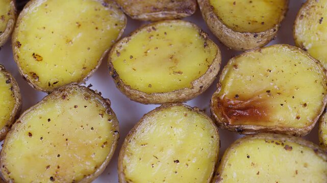 Roasted baby potatoes with herbs. Crunchy ovenroasted fingerling potatoes with seasoning. Homemade crispy roasted small potatoes with herbs and pepper on rustic oven tray