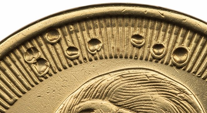 Macro detail of vintage gold coin showing relief engraving and textured surface.